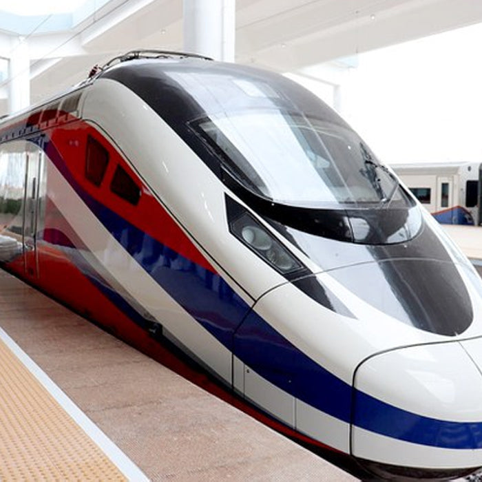 A modern high-speed train with a white and red exterior, arriving at a train station.
